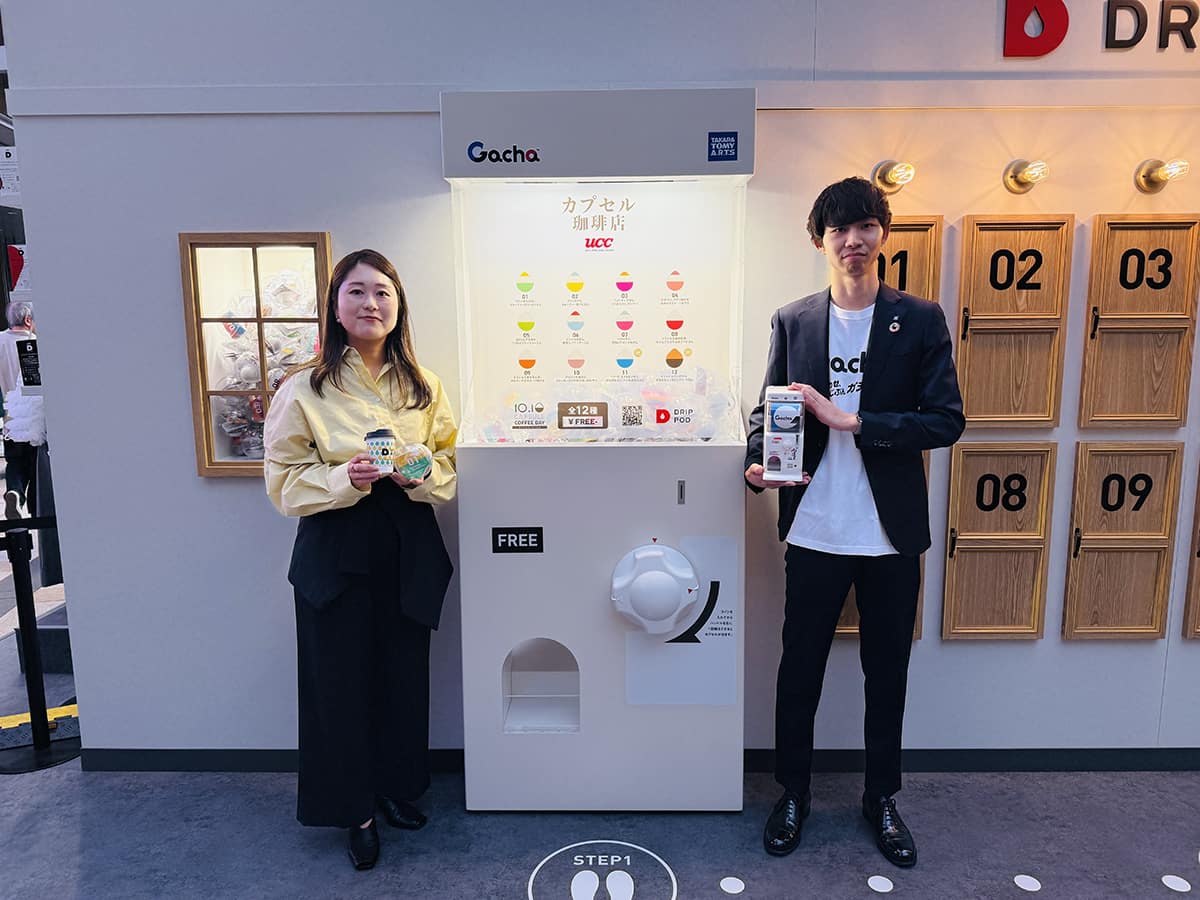 UCC上島珈琲 西川満美子氏(左)と、タカラトミーアーツ 南知輝氏(右)。高さ2mを超えるガチャマシンと共に。