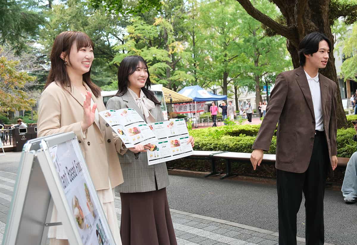 イベント初日にキッチンカーの前で呼び込みをする、プロジェクトに参加している大学生ら。
