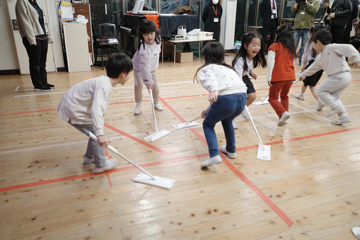 プロジェクトの第1弾では、子どものお手伝いデビューを応援している花王 ホームケア事業部とコラボ。花王が展開するおそうじ住居用掃除用品「クイックル」や食器用洗剤「キュキュット」を使って、お手伝いを体験する園児たち。