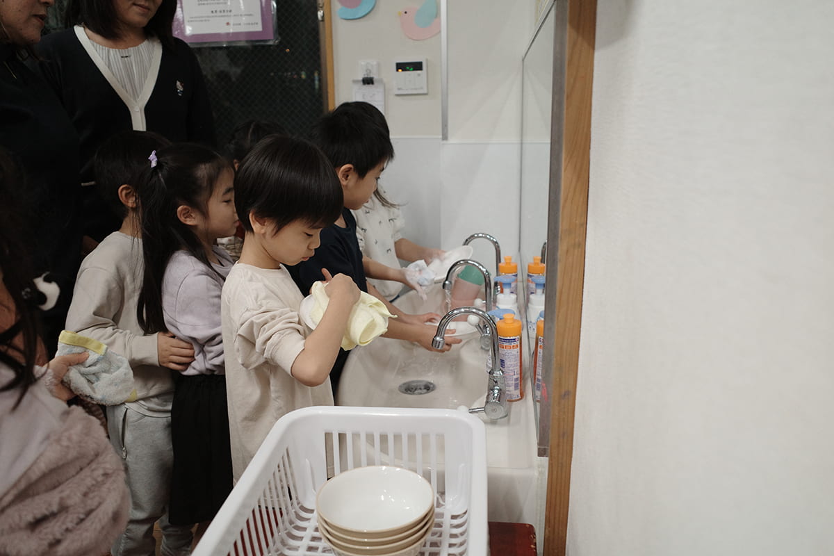 プロジェクトの第1弾では、子どものお手伝いデビューを応援している花王 ホームケア事業部とコラボ。花王が展開するおそうじ住居用掃除用品「クイックル」や食器用洗剤「キュキュット」を使って、お手伝いを体験する園児たち。