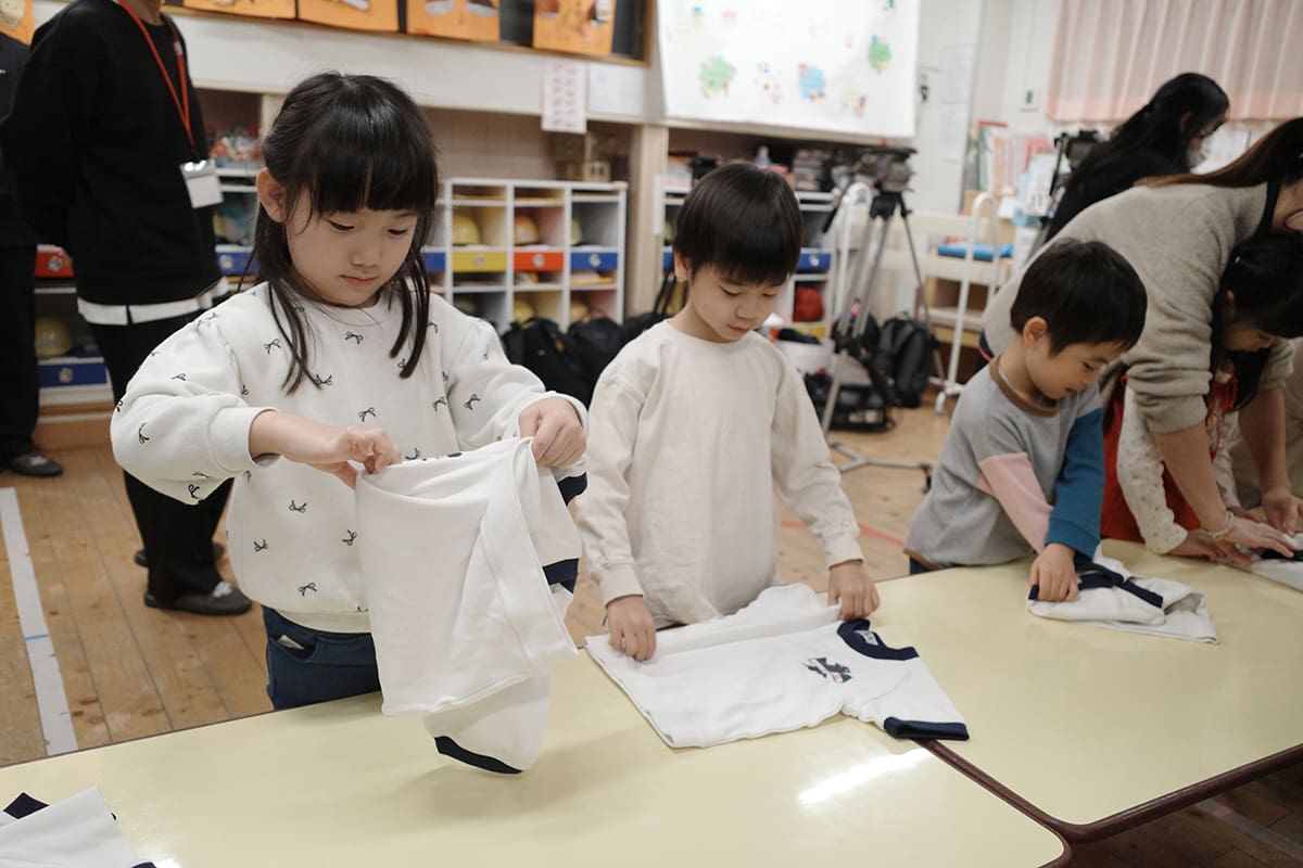 粂井氏が運営するお手伝い塾・粂井塾が全国で教えている「服の3秒たたみ」など、お手伝いデビューにもおすすめな簡単家事術を伝授してもらう園児たち。