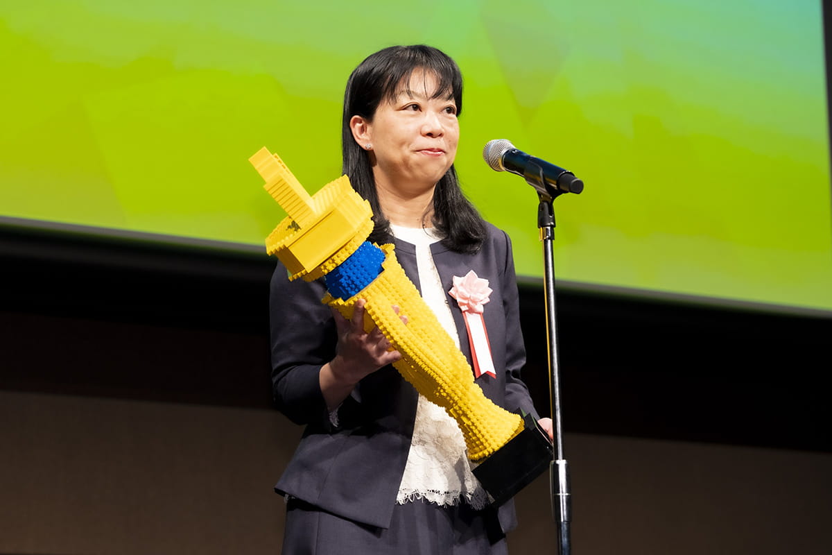 NTTドコモの福岡真美氏。受賞者には、日本初の「レゴ認定プロビルダー」である三井淳平氏が制作したLEGOブロックのトロフィーが授与された