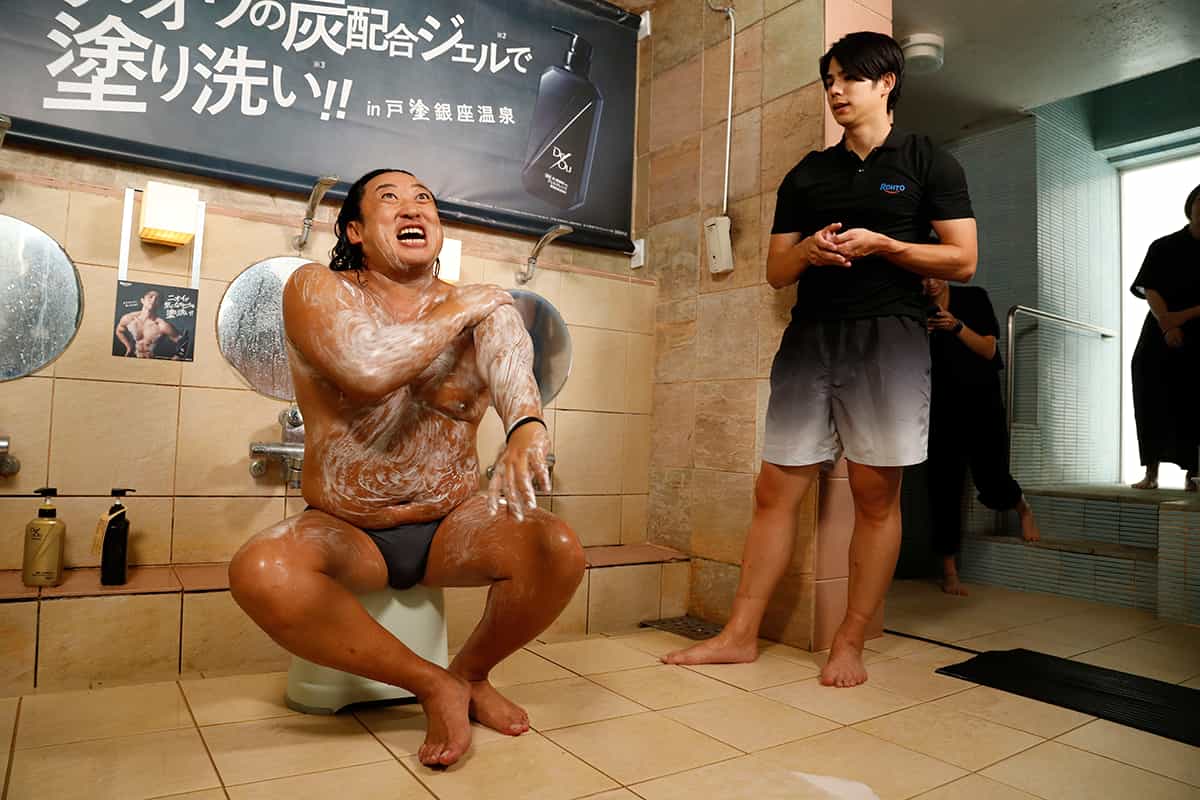 「塗り洗い」を実演する秋山さん。鶴田氏が背中を流す場面も。