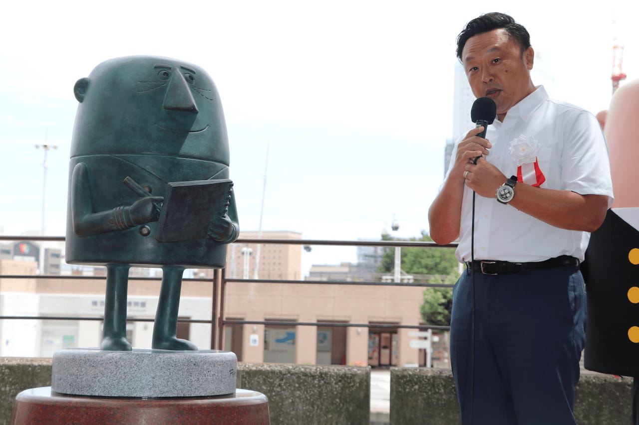 写真 人物 アンクル像とサントリー マーケティング本部 ウイスキー部長の小田氏